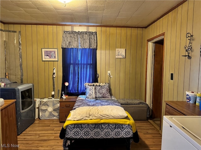 bedroom featuring wooden walls, light hardwood / wood-style floors, and washer and dryer