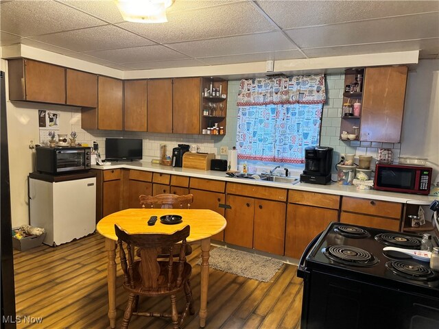 kitchen with decorative backsplash, hardwood / wood-style flooring, a drop ceiling, and electric range oven