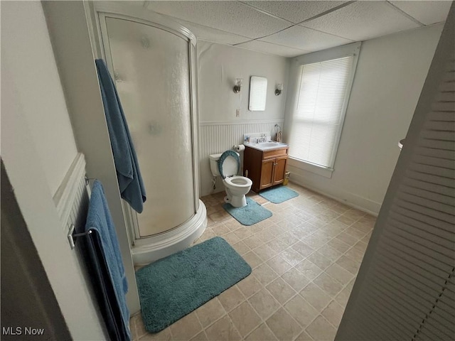 bathroom with a paneled ceiling, a shower with door, vanity, tile patterned floors, and toilet