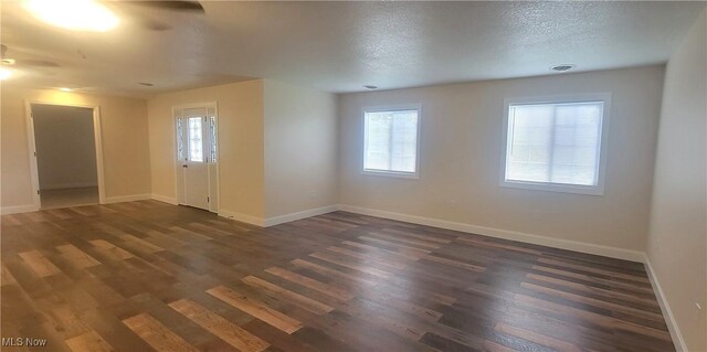 spare room featuring a textured ceiling, dark hardwood / wood-style flooring, plenty of natural light, and ceiling fan