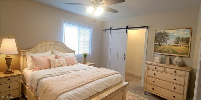 carpeted bedroom featuring ceiling fan and a barn door