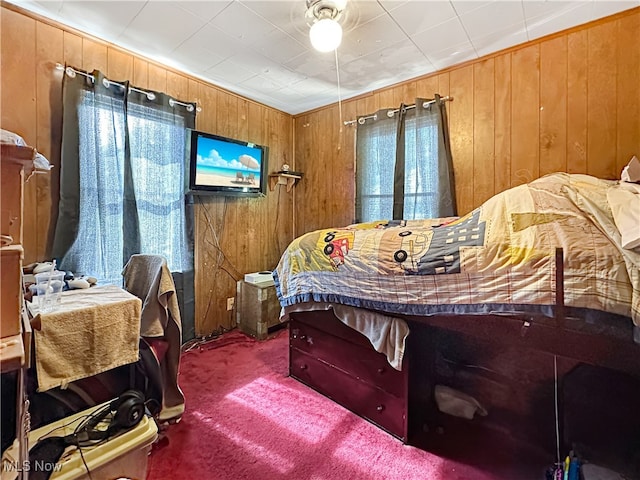 bedroom featuring dark colored carpet and wood walls