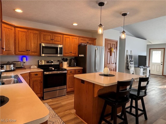 kitchen featuring light hardwood / wood-style flooring, a kitchen island, decorative light fixtures, and appliances with stainless steel finishes