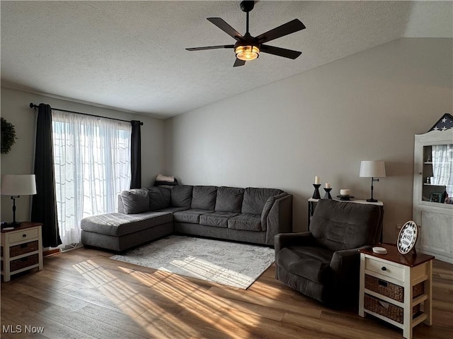 living room featuring hardwood / wood-style flooring, ceiling fan, lofted ceiling, and a textured ceiling