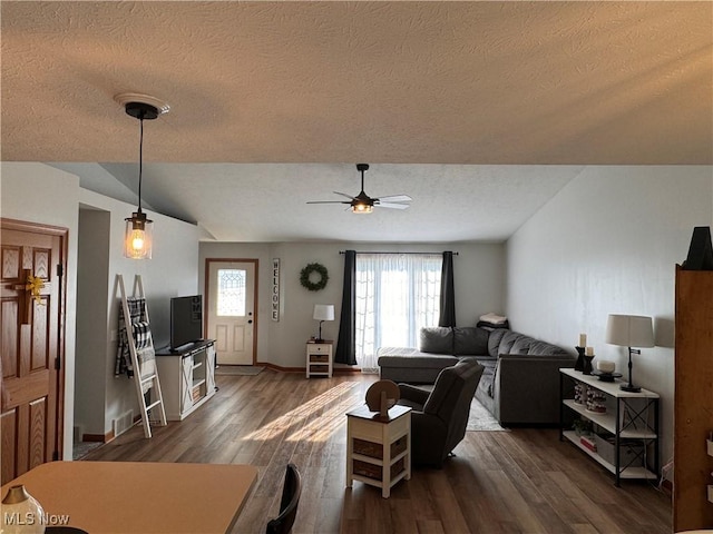 living room with vaulted ceiling, ceiling fan, dark wood-type flooring, and a textured ceiling