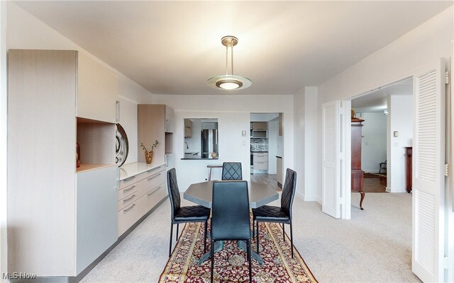 dining space featuring baseboards and light carpet