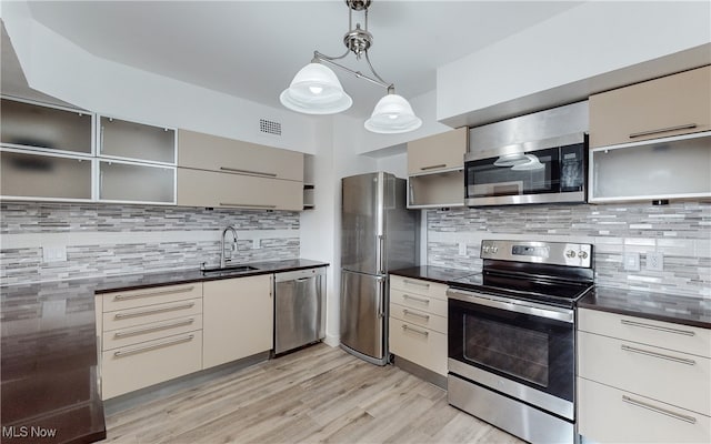 kitchen featuring light wood-type flooring, pendant lighting, appliances with stainless steel finishes, backsplash, and sink