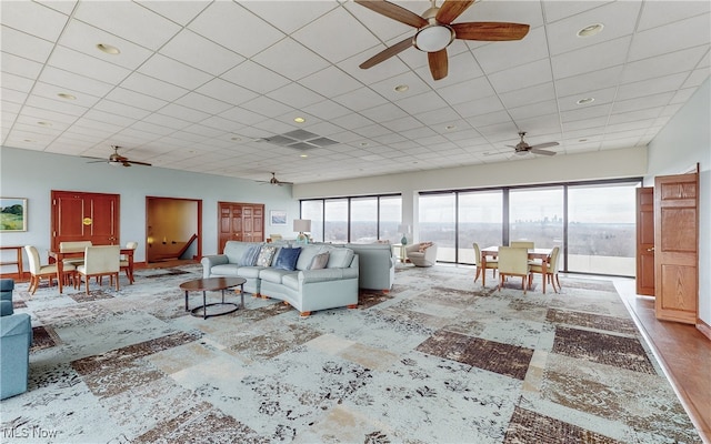 unfurnished living room featuring ceiling fan and a drop ceiling