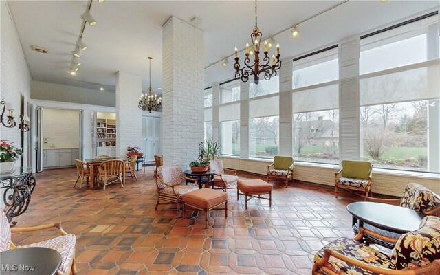 sunroom / solarium featuring a notable chandelier and track lighting
