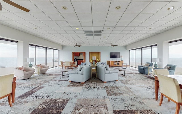 living room featuring a drop ceiling, ceiling fan, and a wealth of natural light