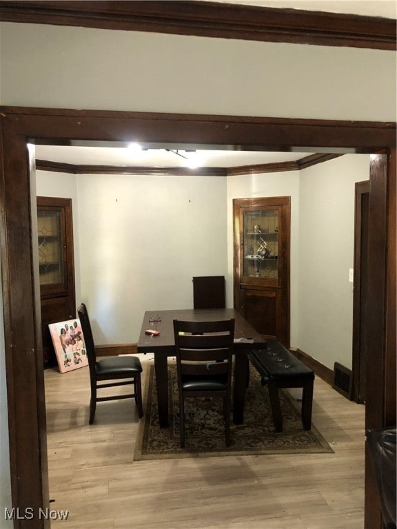 dining space with light hardwood / wood-style flooring and ornamental molding