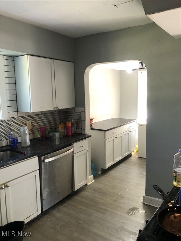 kitchen featuring tasteful backsplash, white cabinets, stainless steel dishwasher, and light hardwood / wood-style floors