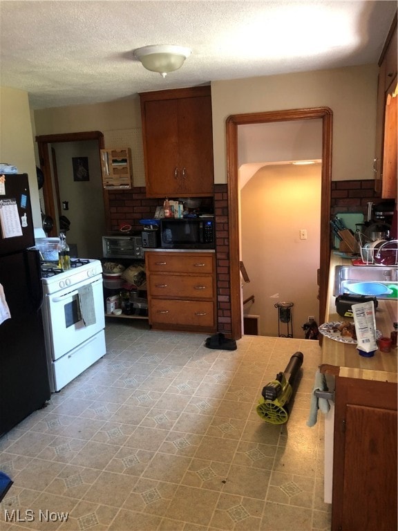 kitchen featuring a textured ceiling, decorative backsplash, sink, light tile patterned flooring, and black appliances