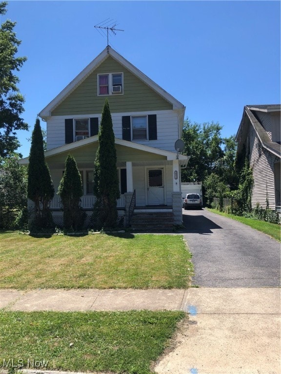 view of front of house featuring a front lawn, covered porch, and a garage