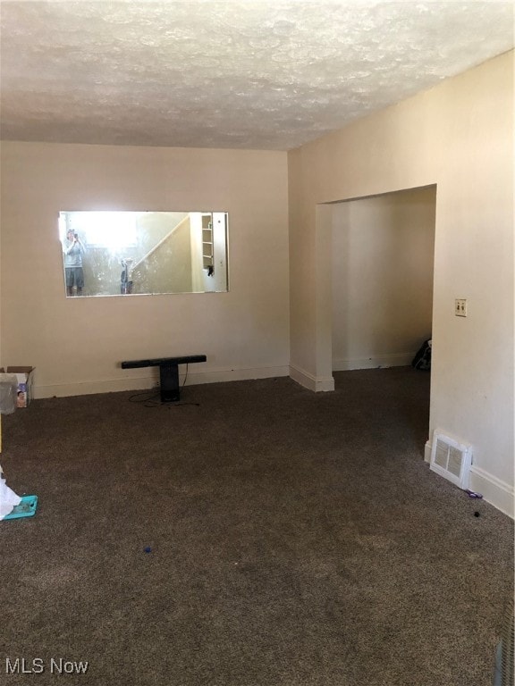 carpeted empty room with a textured ceiling