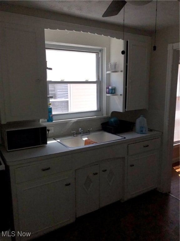 kitchen with ceiling fan, sink, and white cabinetry