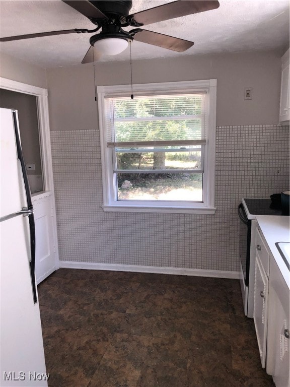 kitchen with dark tile patterned floors, range with electric stovetop, ceiling fan, and white fridge