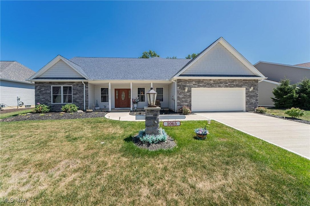 1065 Wayne Trl, Vermilion, OH 44089 - ranch-style house with an attached garage, covered porch, a front yard, stone siding, and concrete driveway