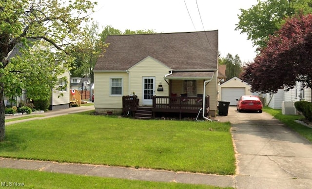 view of front facade featuring a shingled roof, a wooden deck, a front yard, a garage, and an outdoor structure