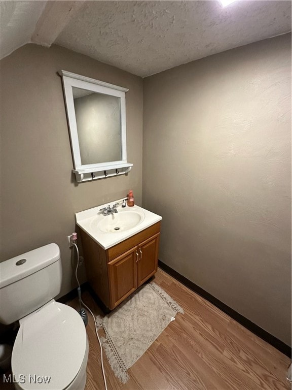 bathroom featuring wood-type flooring, toilet, a textured ceiling, and vanity