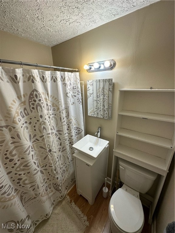 bathroom featuring wood-type flooring, toilet, a textured ceiling, and vanity