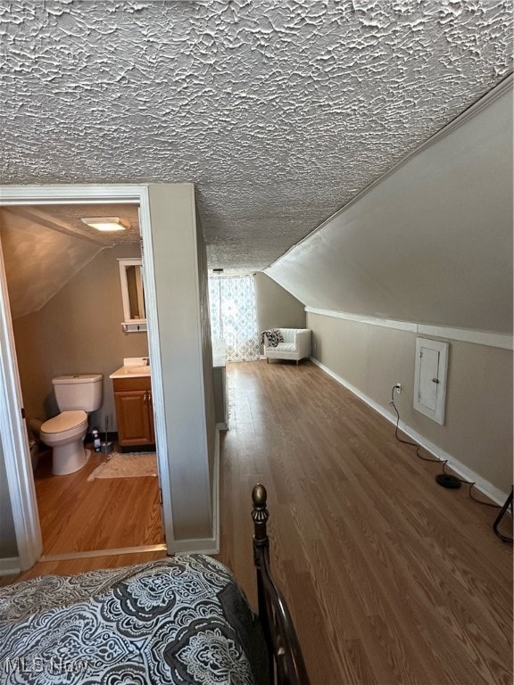 additional living space with a textured ceiling, vaulted ceiling, and wood-type flooring