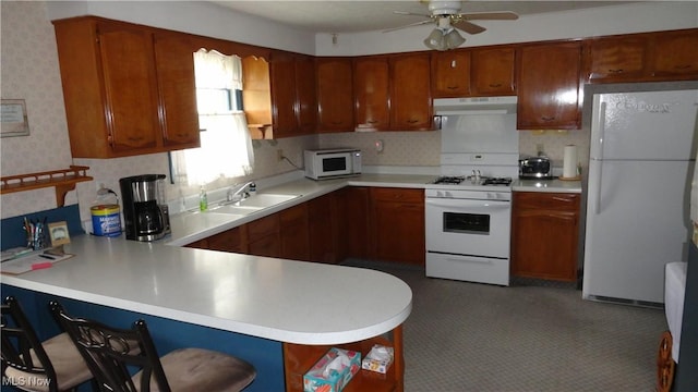 kitchen with sink, white appliances, kitchen peninsula, and ceiling fan