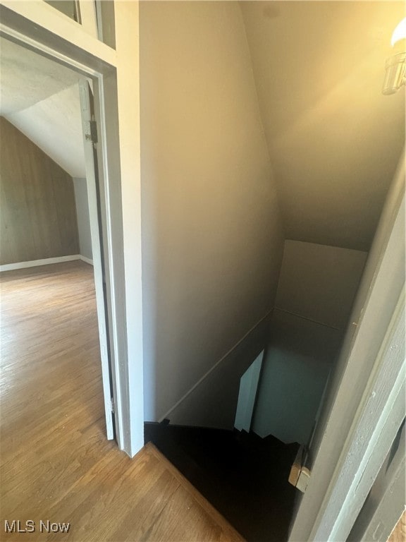 stairway featuring lofted ceiling and hardwood / wood-style flooring