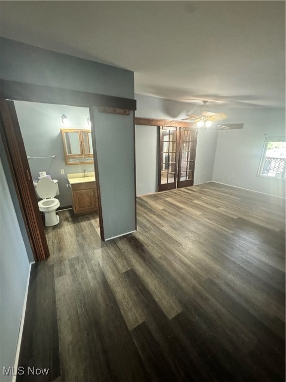 unfurnished bedroom featuring ceiling fan, ensuite bath, sink, and hardwood / wood-style flooring