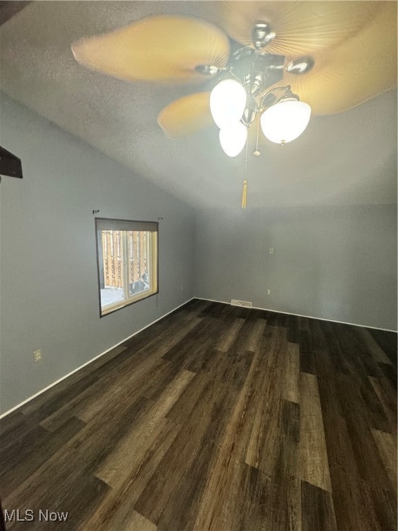 unfurnished room featuring ceiling fan, vaulted ceiling, a textured ceiling, and hardwood / wood-style floors