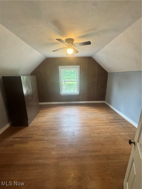 bonus room featuring lofted ceiling, hardwood / wood-style flooring, a textured ceiling, and ceiling fan