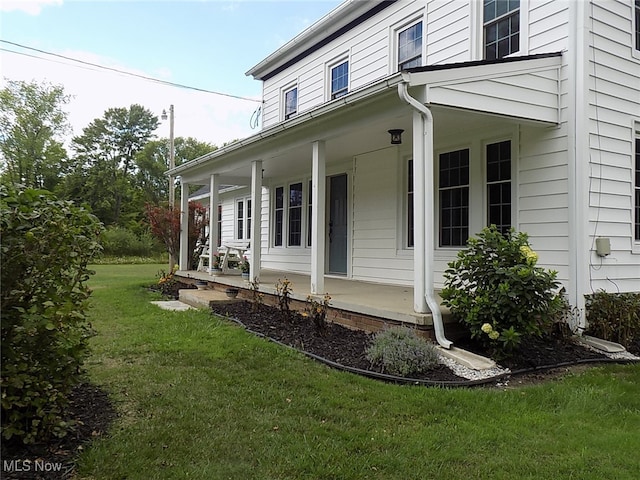 view of side of property with a lawn and covered porch