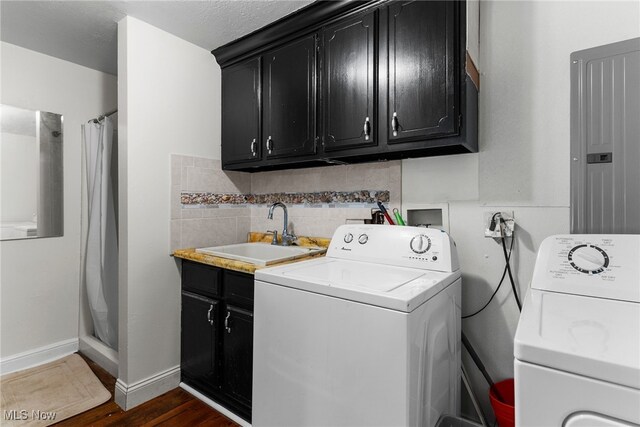 clothes washing area featuring cabinets, sink, washer and dryer, electric panel, and dark hardwood / wood-style floors