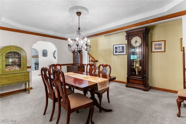 carpeted dining space featuring an inviting chandelier and a tray ceiling