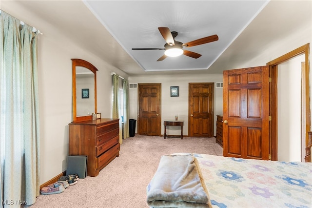 bedroom with ceiling fan, light colored carpet, and a raised ceiling