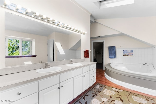 bathroom featuring vanity, a tub to relax in, and wood-type flooring