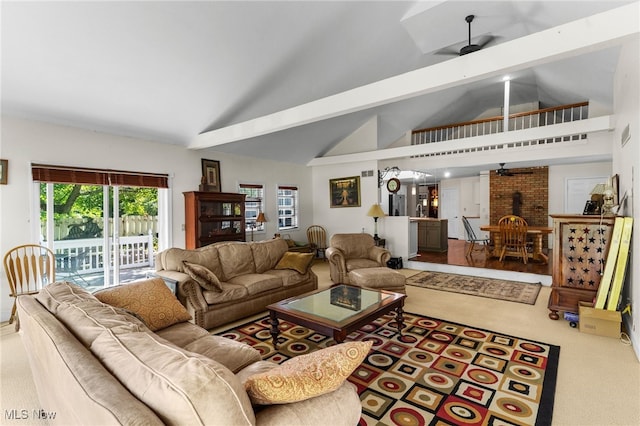 carpeted living room with ceiling fan, high vaulted ceiling, beam ceiling, and brick wall