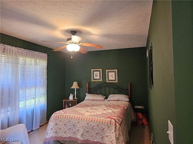 bedroom with ceiling fan, carpet floors, and a textured ceiling