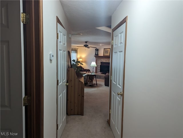 hallway featuring a textured ceiling and light colored carpet