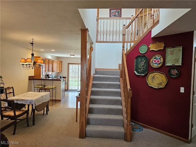 stairway featuring a textured ceiling, carpet floors, and an inviting chandelier