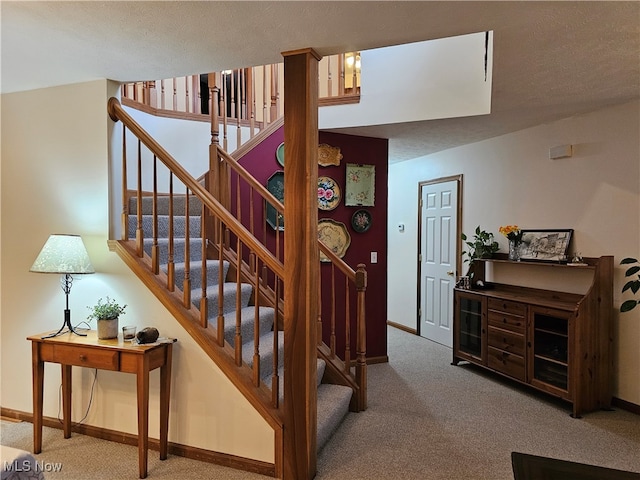 stairway with carpet flooring and a textured ceiling