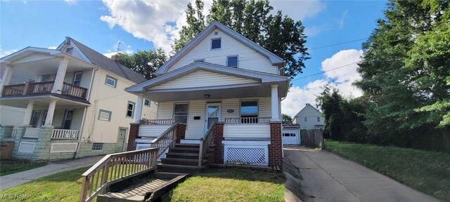 bungalow-style home with a front lawn, a balcony, and covered porch