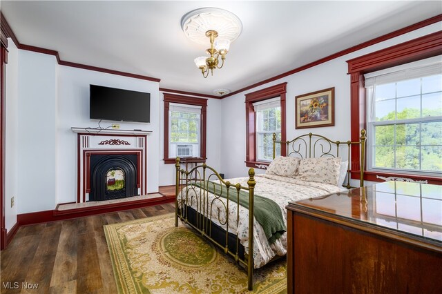 bedroom with ornamental molding, dark hardwood / wood-style flooring, and an inviting chandelier