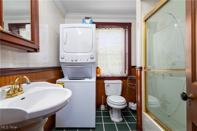 full bathroom with stacked washing maching and dryer, toilet, tile patterned flooring, ornamental molding, and sink