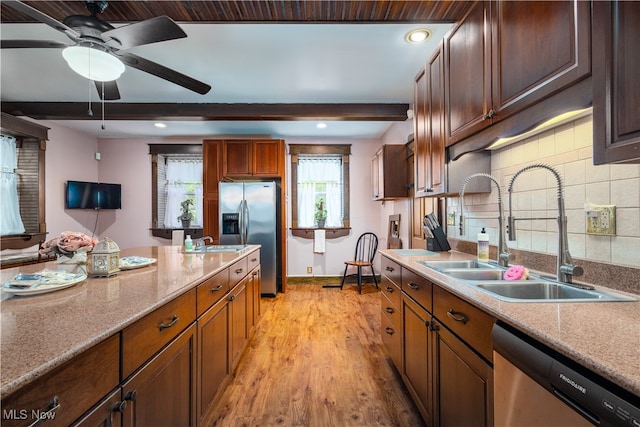 kitchen featuring light wood-type flooring, decorative backsplash, stainless steel appliances, ceiling fan, and sink