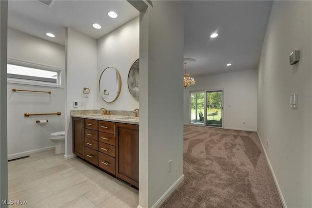 bathroom featuring vanity, an inviting chandelier, and toilet