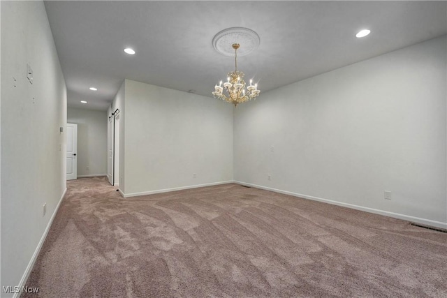 spare room with a barn door, light carpet, and an inviting chandelier