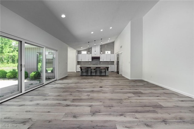 unfurnished living room with high vaulted ceiling and light hardwood / wood-style flooring