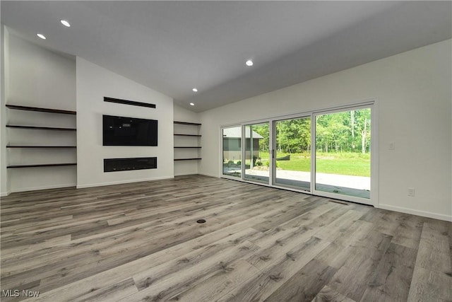 unfurnished living room featuring vaulted ceiling and light hardwood / wood-style flooring