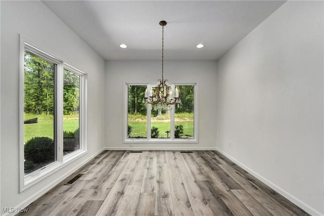 unfurnished dining area with hardwood / wood-style flooring and an inviting chandelier